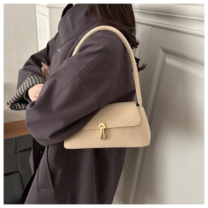 Close-up of a cream baguette shoulder bag featuring a stylish rectangular gold metal clasp