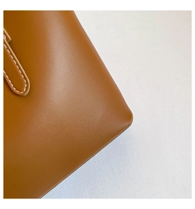 Close-up of brown leather tote bag with white contrast stitching and smooth texture