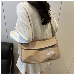 Dettaglio della borsa a tracolla in nylon beige con etichetta fashion e tracolla larga