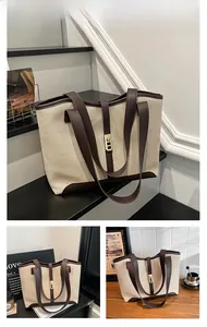 Detail of canvas tote bag showing contrast leather trim and golden metal lock buckle