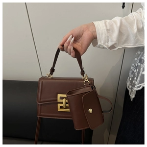 Dettaglio ravvicinato della borsa in pelle marrone scuro con chiusura dorata e borsellino