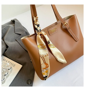 Detail of a brown tote bag with decorative silk scarf and gold adjustable buckle