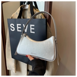 Close-up of silver crescent shoulder bag with metallic wrinkled leather and brand logo