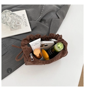 Détail intérieur d'un sac à main plissé marron montrant sa grande capacité et ses accessoires