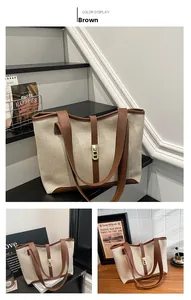 Detail of contrast-color canvas tote bag with brown leather trim and golden metal clasp