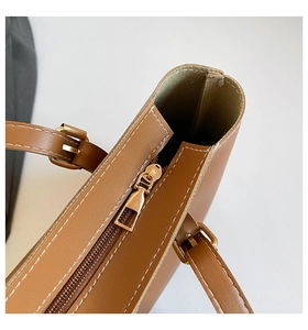 Close-up of golden zipper and white contrast stitching on the brown leather tote bag