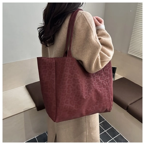 Detail of burgundy leopard print suede tote bag showing texture and shoulder strap drop