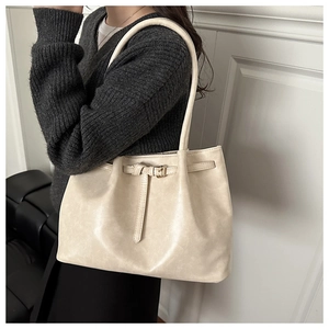 Side view of a large cream tote bag on a model showing the shoulder strap and buckle detail