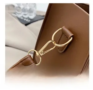Close-up of premium light gold lobster clasp and stitching on brown leather tote bag