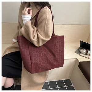 Detail of burgundy leopard print suede tote bag worn on shoulder for winter fashion