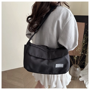 Rear view of model wearing black waterproof nylon messenger bag with fashion patch