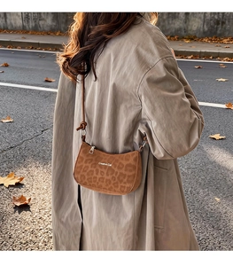 Close-up of leopard print shoulder bag with Creative Cat logo on autumn street