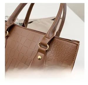 Detailed close-up of brown crocodile embossed leather tote bag with shiny gold hardware