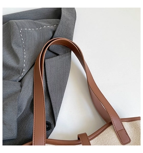 Close-up of canvas tote bag showing brown leather shoulder straps and stitched edge detail