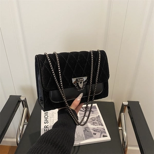 Quilted black velvet shoulder bag with silver chain strap and metal lock closure