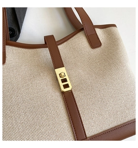 Close-up of canvas and brown leather tote bag with gold metal twist lock and stitching