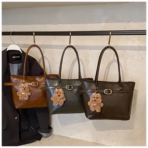 Detailed view of leather tote bags in caramel and grey with cute puppy pendant charms