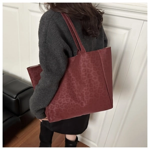 Macro detail of wine red leopard print tote bag with reinforced stitching and long strap
