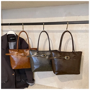 Detailed view of three tote bags in caramel, grey, and coffee colors with golden buckle
