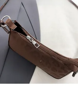 Detail of silver metal zipper and brand logo on brown suede shoulder bag