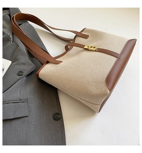 Detail of off-white canvas tote with brown leather trim and golden metal turn-lock closure