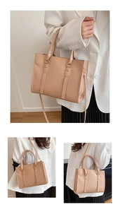 Detail view of beige crocodile embossed tote bag with gold hardware and top handle
