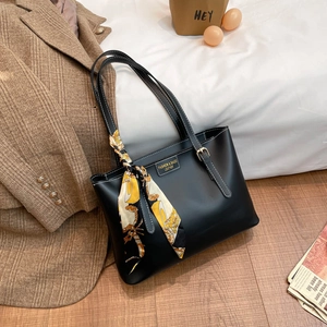 Large black faux leather tote bag with decorative patterned scarf and sleek metal plate