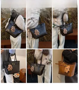 Detail view of leather tote bags in black and brown with plush bear charms and side buckles