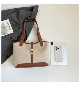 Top view of beige canvas tote bag with brown leather trim and golden metal buckle details