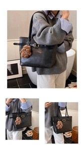 Detail of black faux leather tote bag featuring golden buckle and brown teddy bear charm