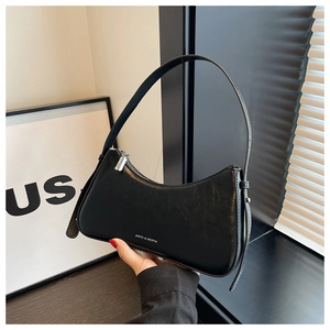 Detail of black crescent shoulder bag with glossy PU texture and silver zipper finish