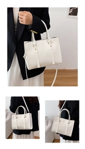 Detail of white crocodile pattern tote bag with gold hardware and removable shoulder strap