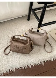Detail view of cylindrical pillow bags in bronze and taupe with brushed metal texture