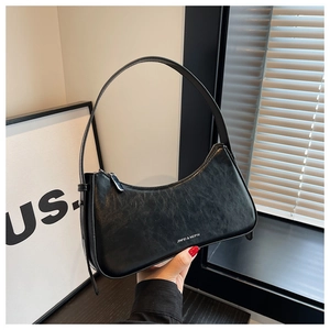 Close-up of black leather moon bag with brand logo and silver zipper details