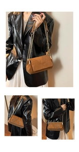 Detail of brown suede messenger bag with gold chain strap and cross stitching design