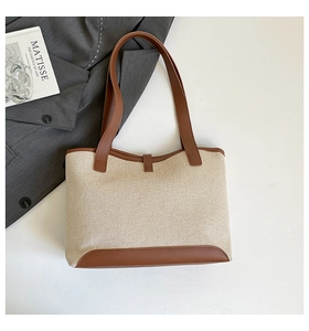 Detail view of canvas tote with brown leather trim and sturdy straps on a blazer