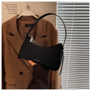 Close-up of black crescent shoulder bag with silver zipper and brand lettering