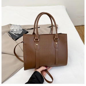 Detail of dark brown crocodile texture tote bag with gold rivets in elegant setting