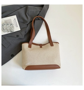 Detail of canvas tote bag with brown leather trim and sturdy reinforced handles