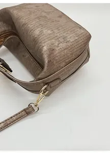 Dettaglio ravvicinato della borsa dorata plissettata con tracolla rimovibile e gancio in metallo