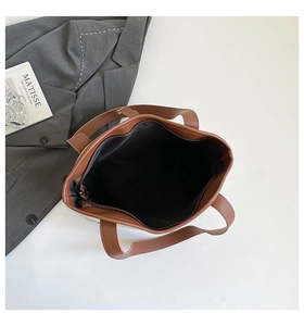 Detailed interior of brown tote bag with black lining and a secure zipper pocket