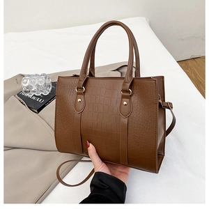 Detail of brown crocodile embossed faux leather handbag with vintage gold hardware