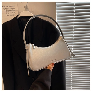 Detail of silver crescent armpit bag with metallic finish and embossed logo on the side