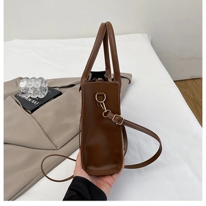 Detail view of the side depth and metal hook on a dark brown leather handbag