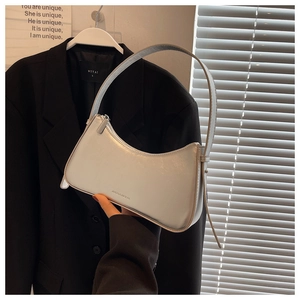 Detail of pearl white glossy hobo bag with silver zipper and sleek leather strap