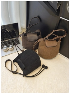 Three bucket bags in black, coffee, and khaki shown with suede stitching on a white rug