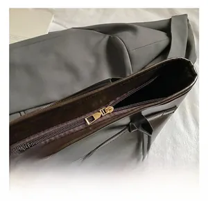 Detailed macro view of high-quality smooth zipper and logo on a vintage brown leather tote bag