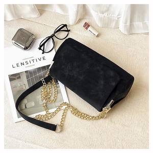 Detail of black matte tote bag with cross-stitched texture and gold chain strap