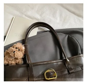 Detail of dark brown leather tote featuring gold buckles and a cute plush dog charm