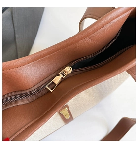 Close-up of golden zipper closure and stitching detail on canvas leather tote bag